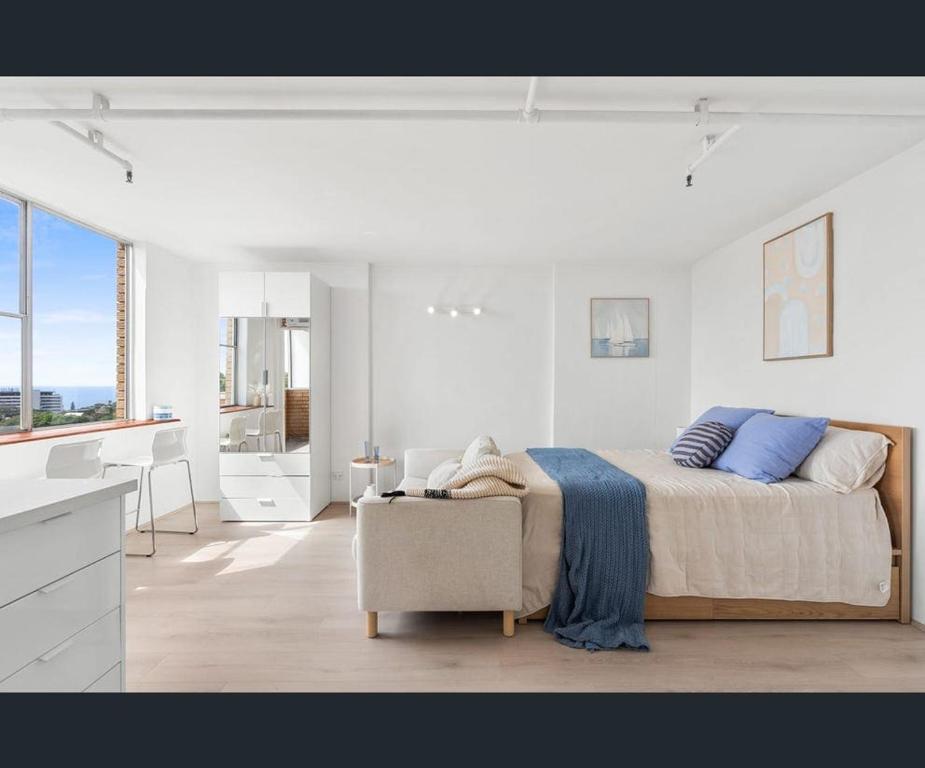 ein weißes Schlafzimmer mit einem Bett und einem Stuhl in der Unterkunft Bondi Beach Studio with an ocean view in Sydney