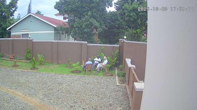 a group of people sitting on a bench in a backyard at Palm Suites Unit3 in Mbale