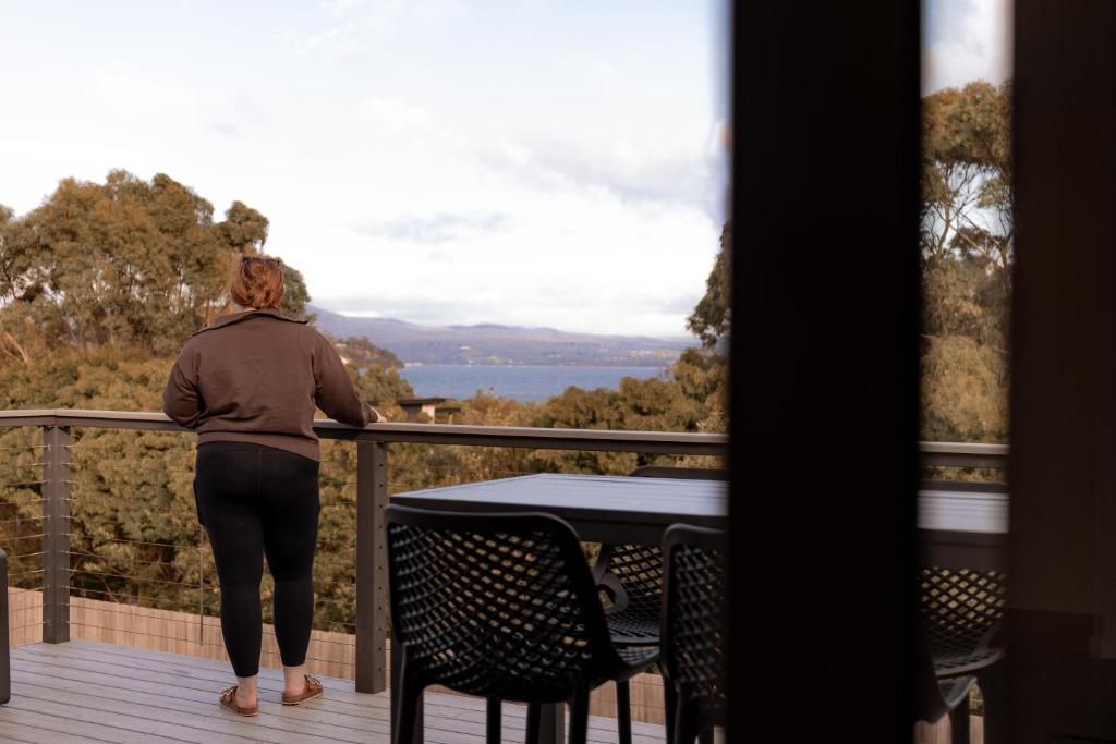 een vrouw op een balkon met uitzicht op de oceaan bij House Peron - Bayside Luxury in St Helens