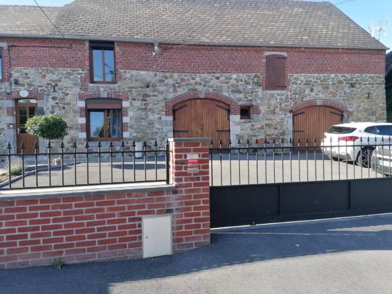 une maison en briques avec deux portes de garage et une clôture dans l'établissement La ferme des souvenirs 3, à Felleries