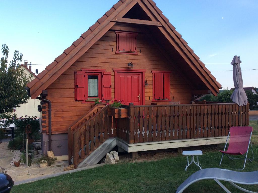 Casa pequeña con puertas rojas y terraza de madera. en Chalet Colline et Lou en Wintzfelden