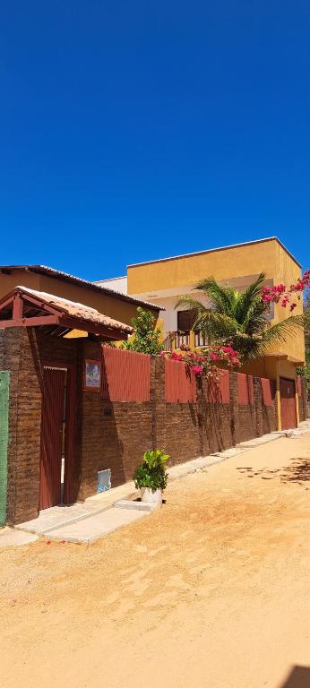 a brick building with a fence in front of it at Casa Strela Jericoacoara in Jericoacoara