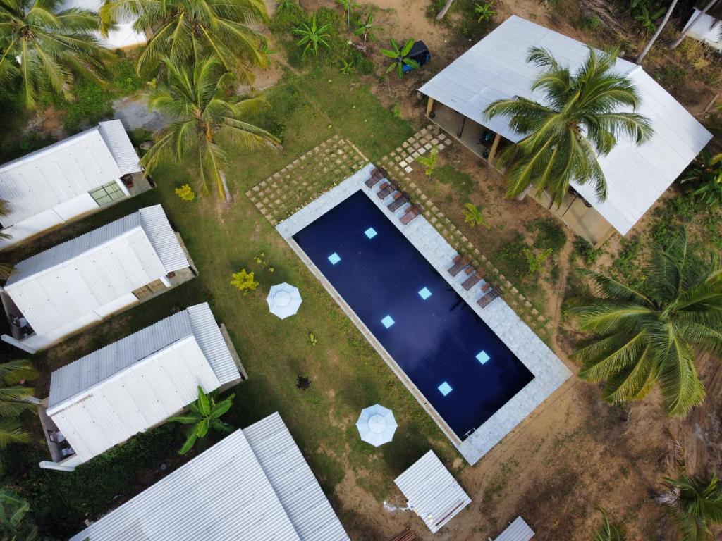 an overhead view of a swimming pool in a yard with palm trees at White House Safari Cottage in Udawalawe