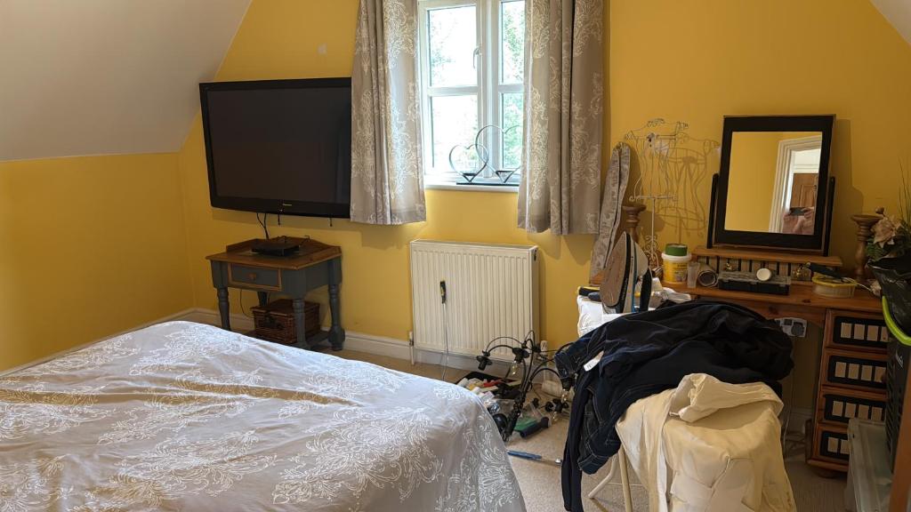 a bedroom with a bed and a flat screen tv at Silsoe Cottage B&B in Silsoe