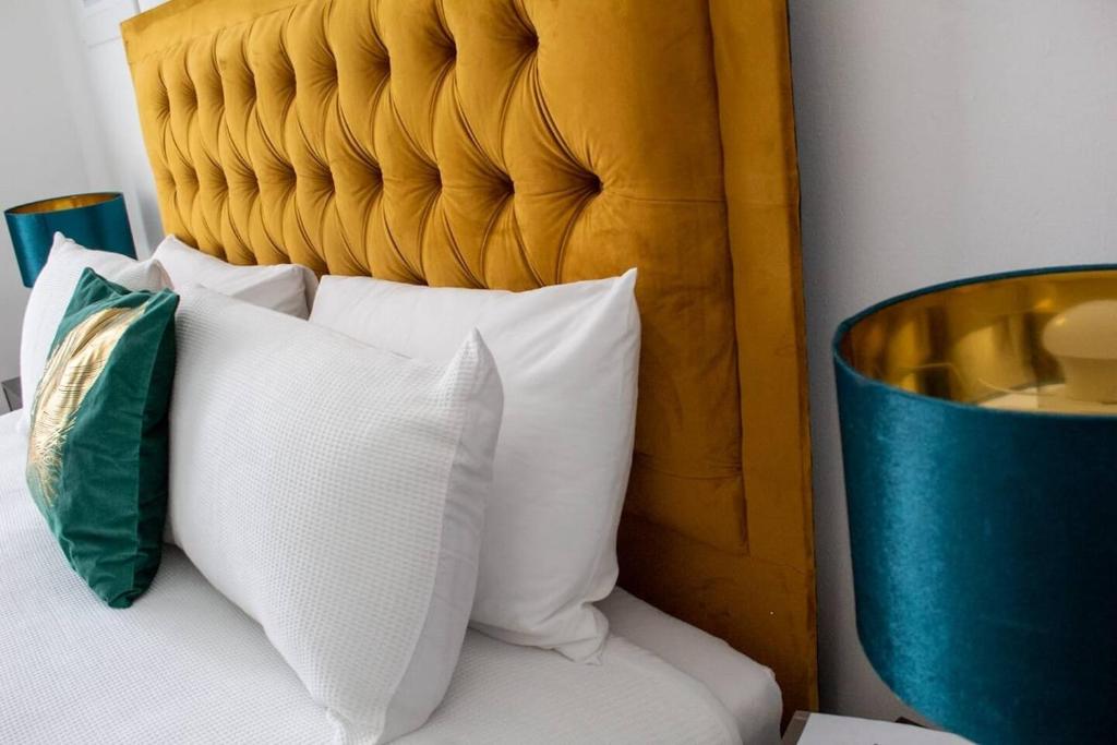 ein Bett mit weißen Kissen und einem Kopfteil aus Holz in der Unterkunft Central Location! 15 mins to Airport 2 mins to High Street and Station FREE PARKING!! in Birmingham