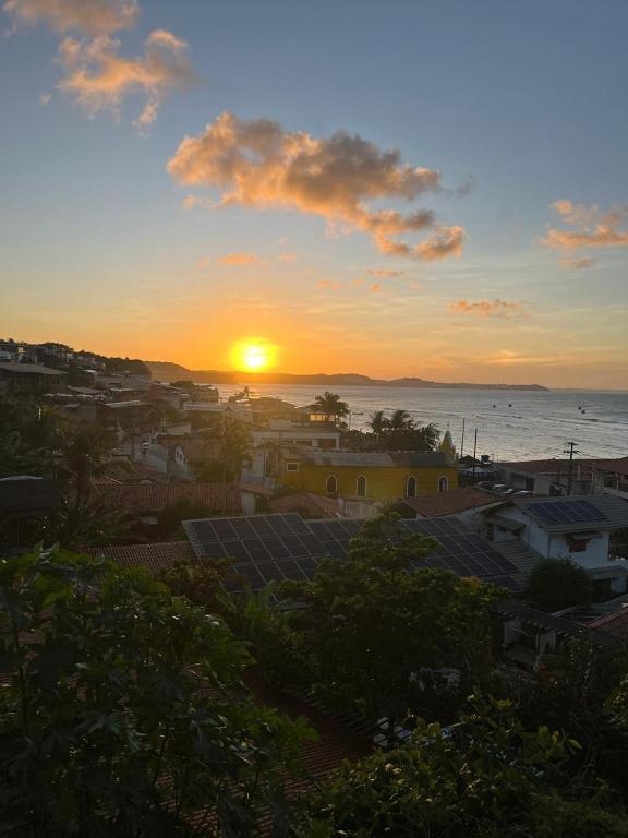 Una puesta de sol sobre una ciudad con el océano y las casas. en VistaSurf Suites, en Pipa