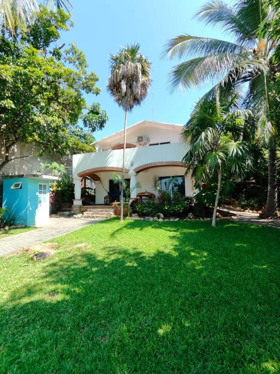 a house with palm trees in front of a yard at Casa Los Mangales in Brisas de Zicatela