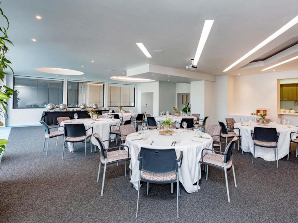 a banquet hall with white tables and chairs at BreakFree on Cashel, an Accor Hotel in Christchurch