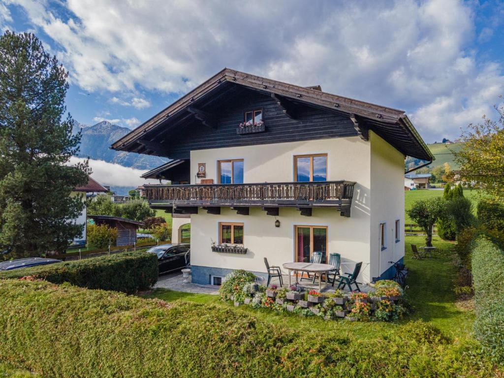a white house with a balcony and a table at Tauernhaus Madelief in Piesendorf