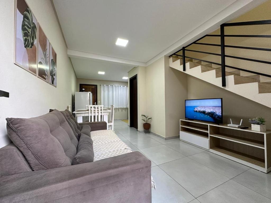 Una sala de estar con un sofá y un televisor de pantalla plana. en Casa Familiar - Próximo ao Aeroporto - WI-FI - Garagem Privativa GEM17, en Joinville