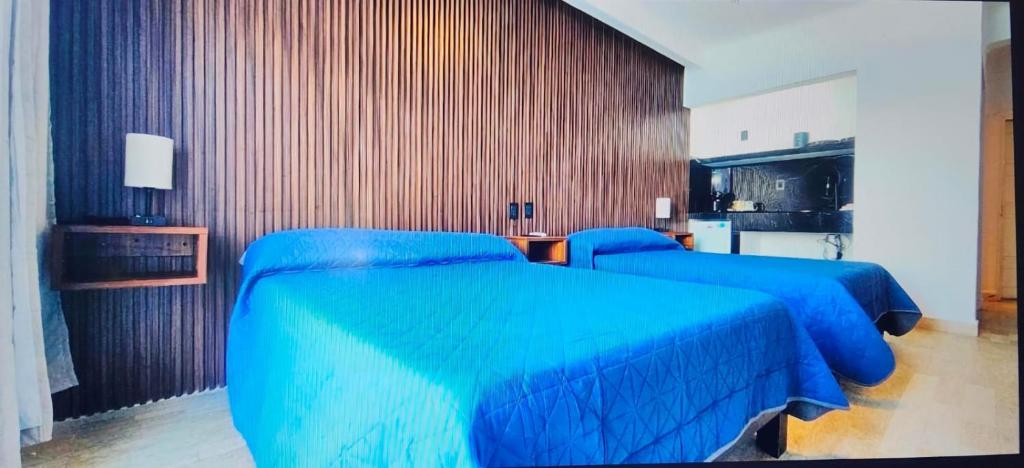 two beds in a room with blue sheets at Suite Luna in Cancún