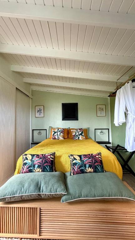 een slaapkamer met een groot geel bed met kussens bij Cosy place with sea view in Oyster Pond