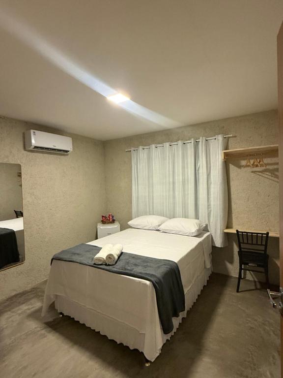 a bedroom with a large white bed with a window at Pousada Arena 165 in Murici