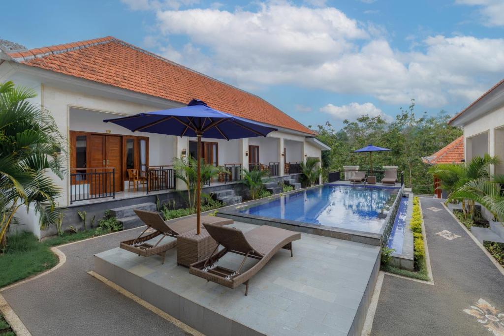 a house with a swimming pool with chairs and an umbrella at Memela Bungalow in Nusa Penida