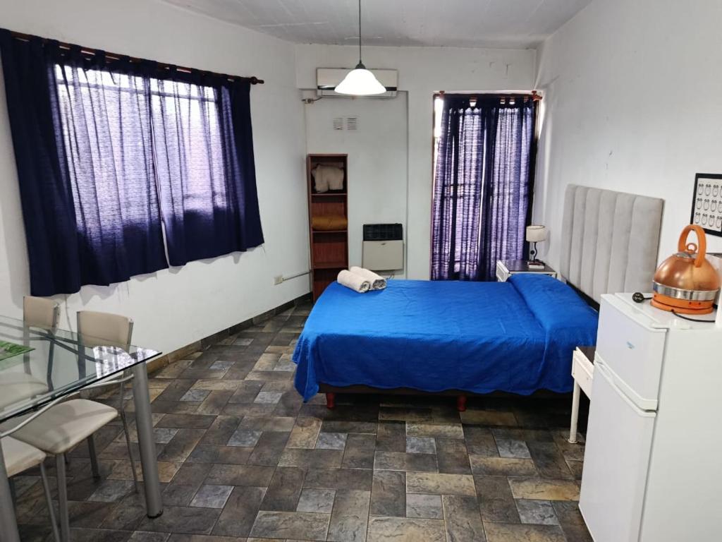 a bedroom with a blue bed and a table and chairs at Alojamiento Entero con Excelente Ubicación in Morón