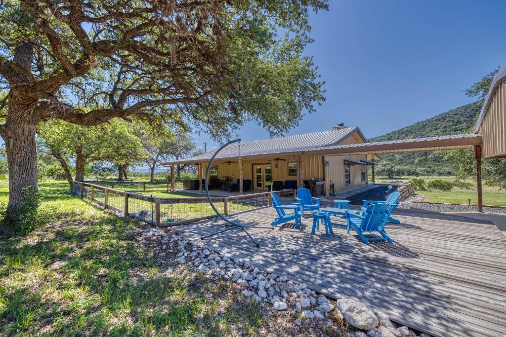 a wooden deck with blue chairs and a house at Frio Hills Hideaway in Leakey
