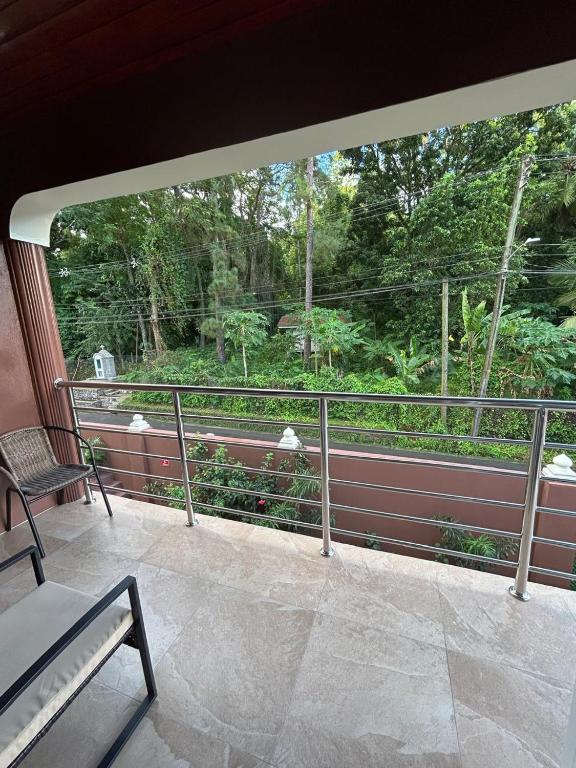 a balcony with a view of a forest through a window at Agape Suites-Room 4- 1st Floor in Soufrière