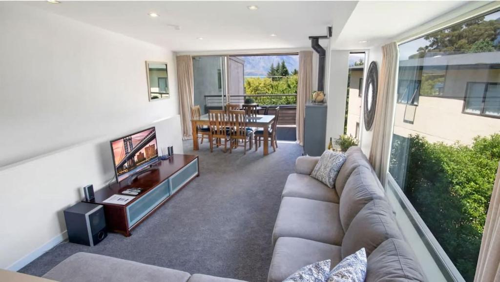 a living room with a couch and a television at The Alps Apartment in Queenstown