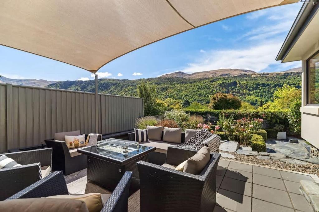 an outdoor patio with a table and chairs and mountains at Botanical Bliss in Arrowtown