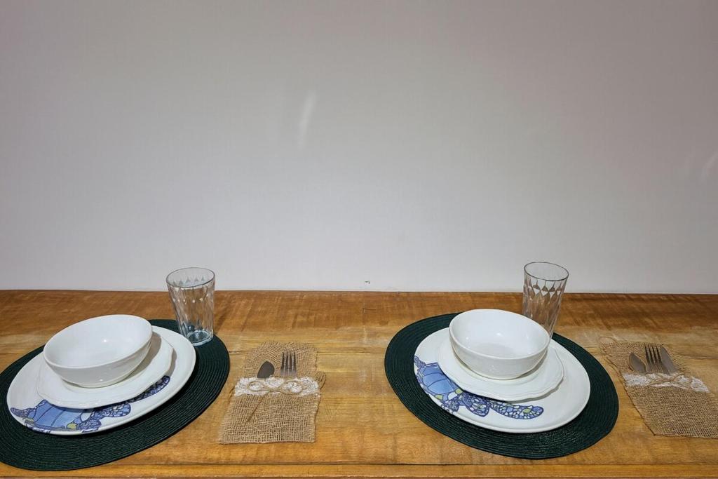 a table with two plates and glasses on a table at Studio Privativo a 3 min Centro c Ar Condicionado in Uberlândia