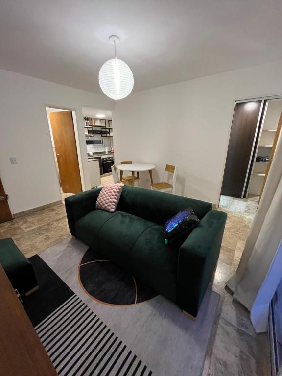 Departamento ideal encantador en morón centro في مورون: غرفة معيشة مع أريكة خضراء وطاولة