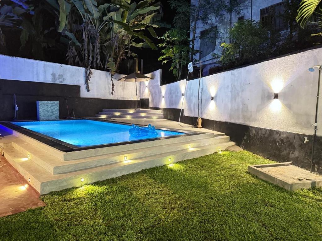 Pineapple Surf Villa في آهانغاما: وجود مسبح في حديقة خلفية في الليل مع وجود أضواء