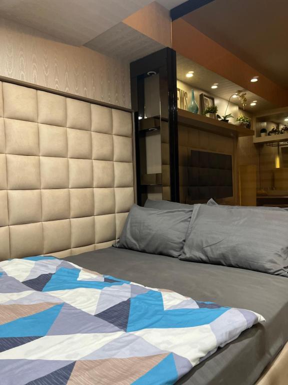 Un dormitorio con una cama con un cabecero grande. en Shell Residences near MOA and NAIA by Mae, en Manila
