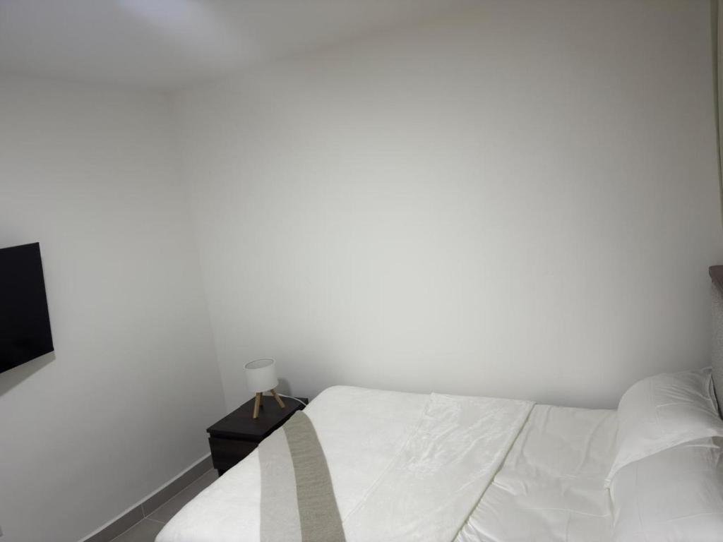 een witte slaapkamer met een bed en een nachtkastje bij Palmera 402 in Punta Cana