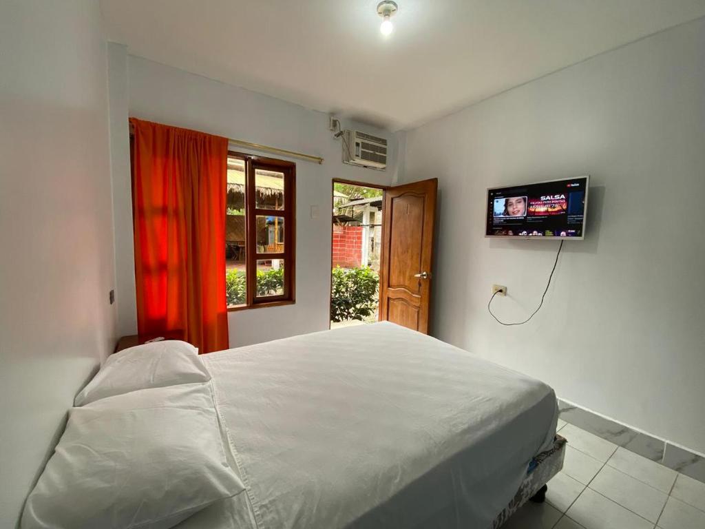 a bedroom with a white bed and a television at Tierra y Mar in Montañita