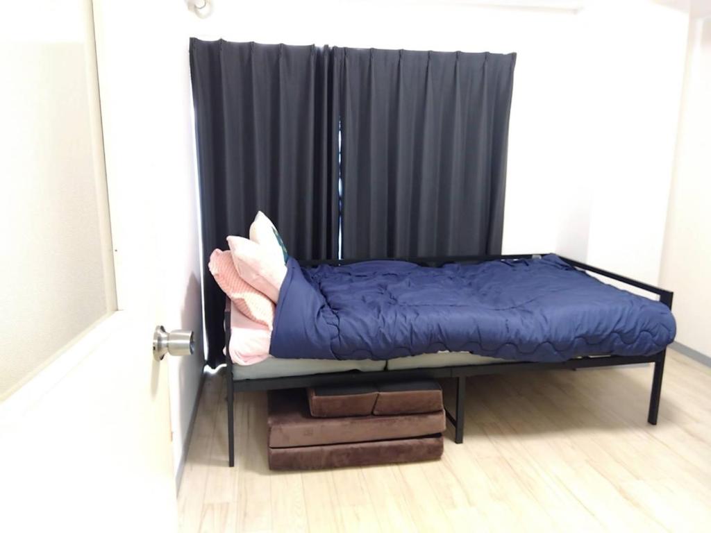 a bed in a room with a black curtain at SunandMoonホテル401 in Tokyo