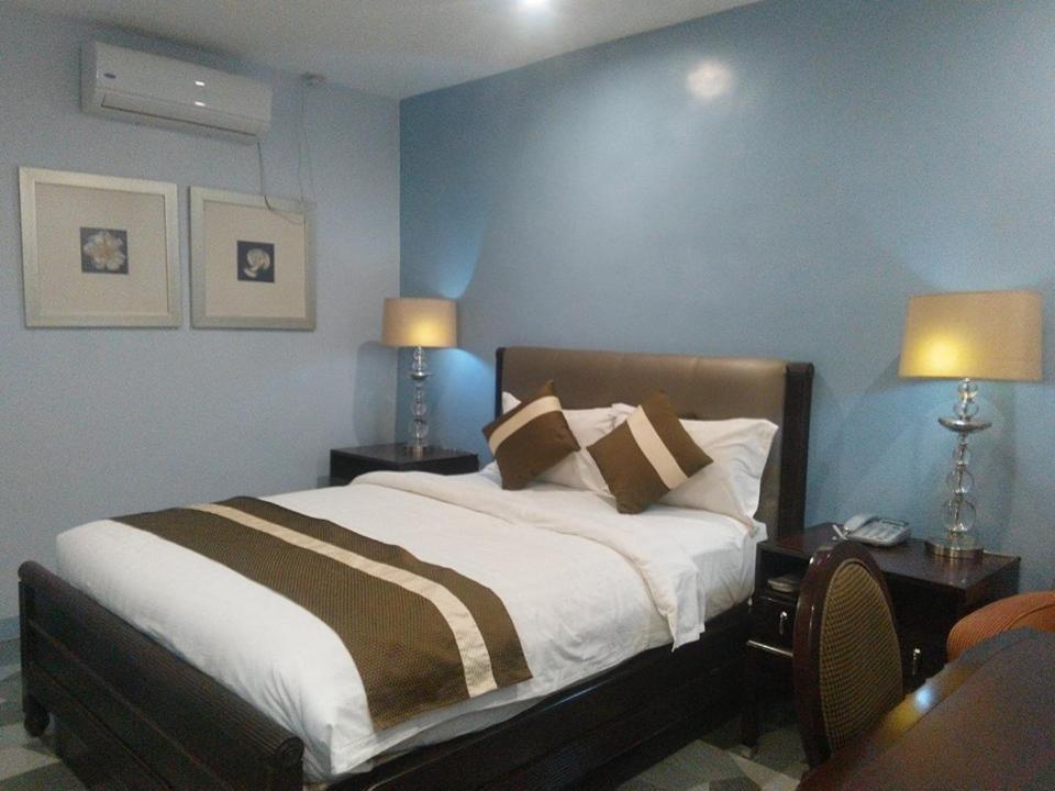 a bedroom with a bed with two tables and two lamps at Subic Bay View Diamond Hotel in Olongapo