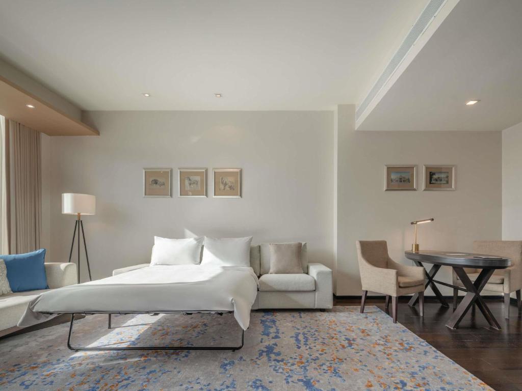 A suite-style room combines a low bed, sofa seating and a small dining or work table.