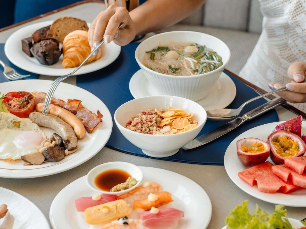A generously styled breakfast spread combining hot dishes, fruit, bread, and noodles.