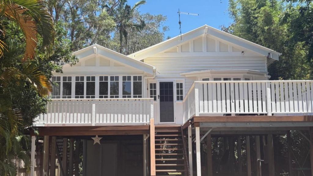 a white house with a porch and a deck at Welcome To Queenslander By The Sea in South Golden Beach