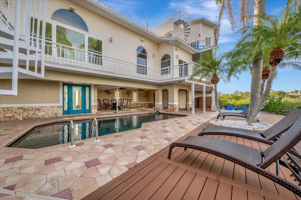 a house with a swimming pool and two chairs at 6B Waterfront Game Room Pool Hot Tub Dock in Palm Harbor