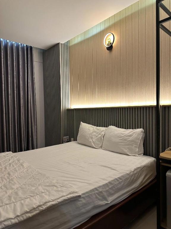 a bed with white sheets and a clock on the wall at ABC HOTEL BÌNH TÂN in Ho Chi Minh City