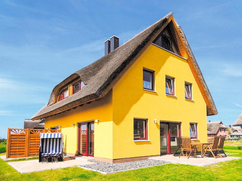 ein gelbes Haus mit einem Strohdach in der Unterkunft Reetdachhaus mit Sauna und Boddenblick - D 128.036 in Vieregge