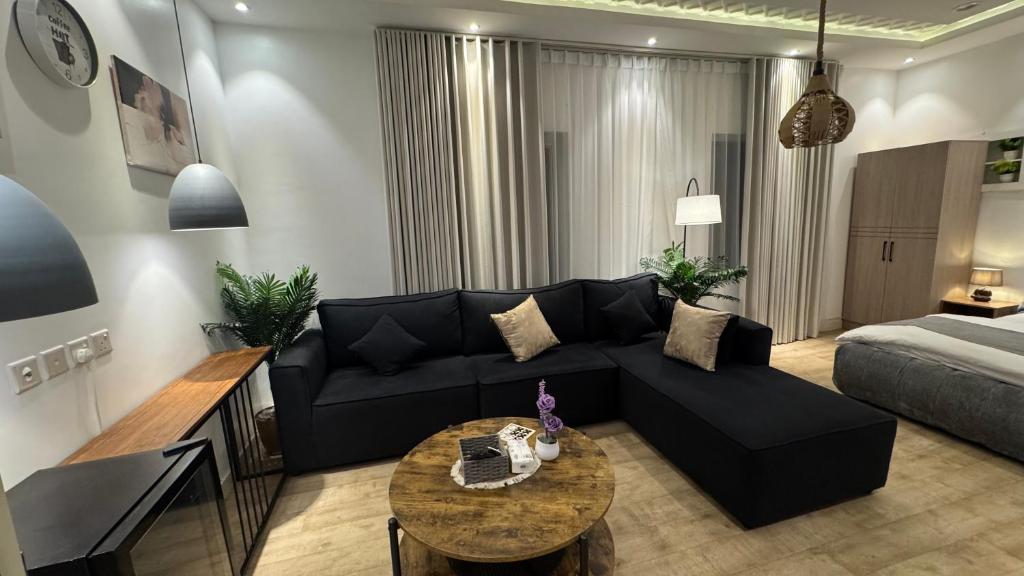 استديو بوصول ذاتي غرفتين في جازان: غرفة معيشة مع أريكة سوداء وطاولة