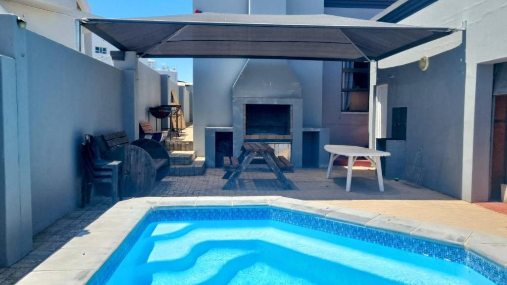 a patio with a swimming pool and an umbrella at Linaria Beach House in Britannia Bay