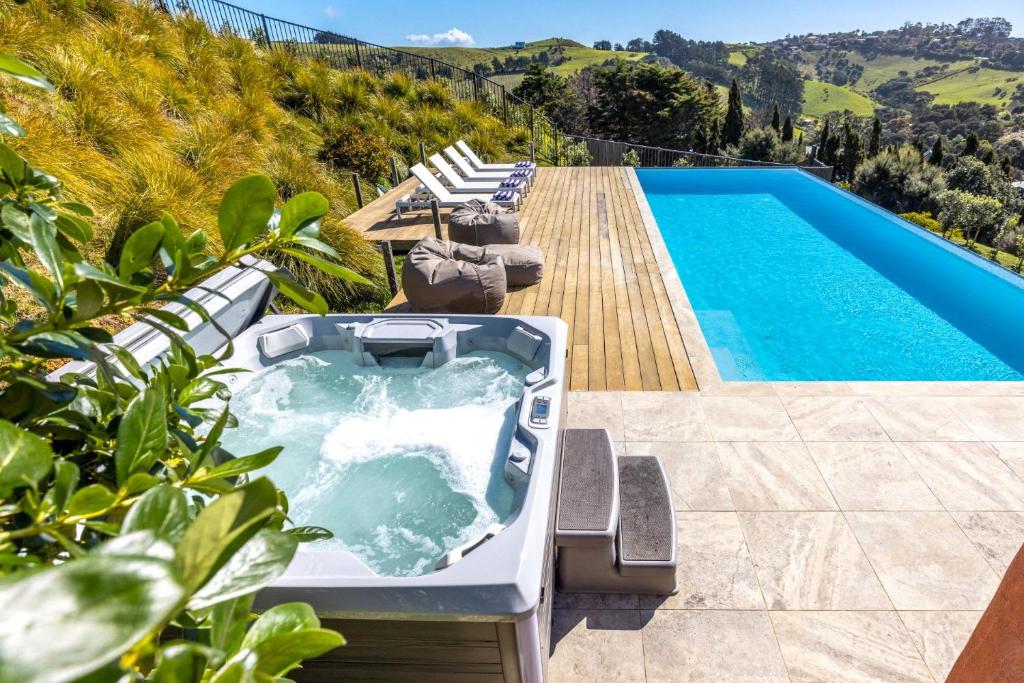 a bath tub sitting on a deck next to a swimming pool at The Villino at Cypress Ridge Estate - Stay Waiheke in Onetangi