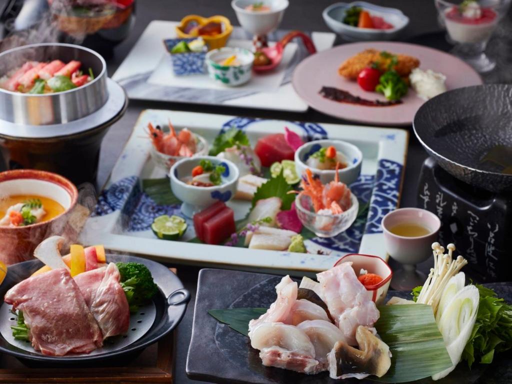 une table avec des assiettes et des bols de nourriture dans l'établissement KAMENOI HOTEL Arima, à Kobe