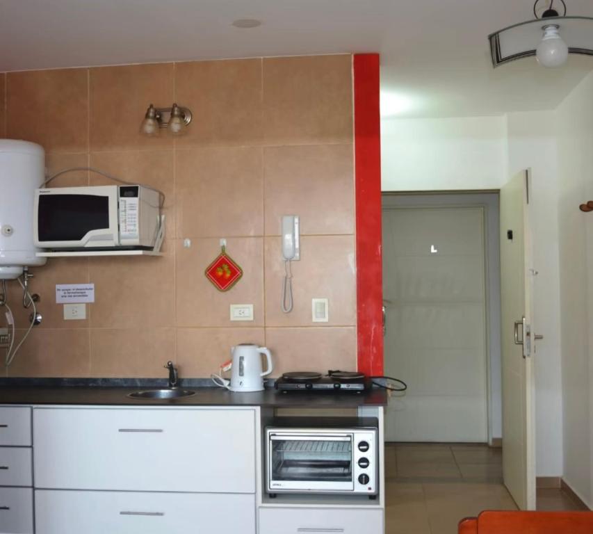 een kleine keuken met een magnetron en een fornuis bij Monoambiente en Miramar in Miramar