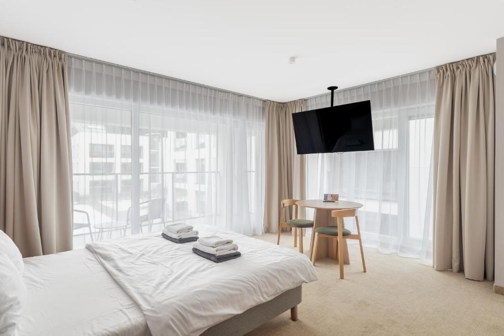 a bedroom with a bed and a table and a television at Hidden Coast - Premium Seaside Apartments with Pool, 2-Minute Walk to the Beach in Łukęcin