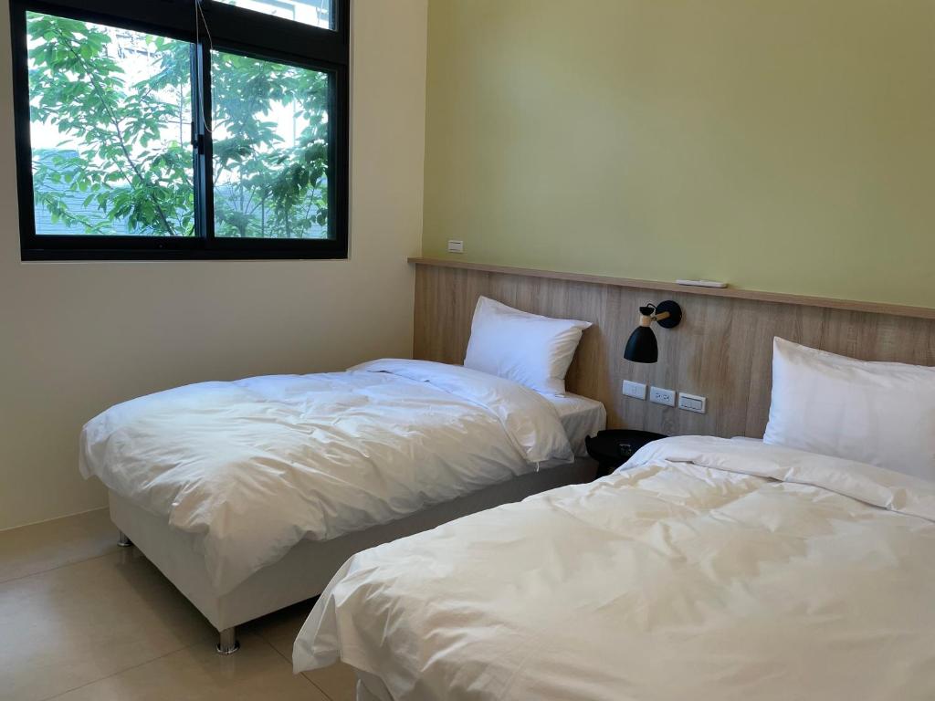 a bedroom with two beds and a window at Yun Tian Homestay in Jincheng