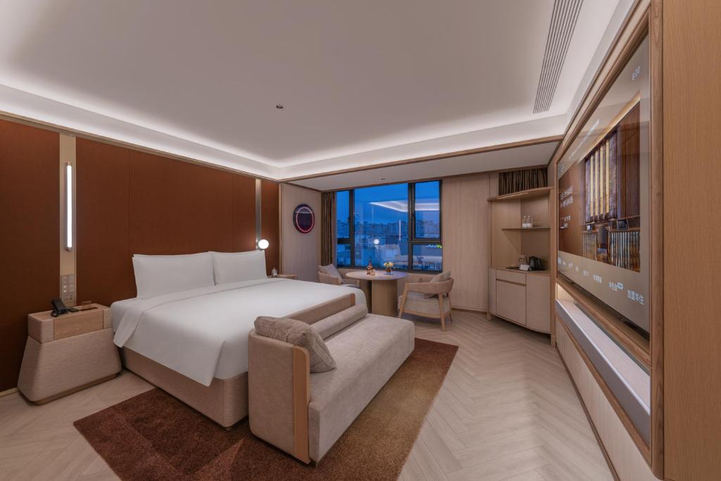 a bedroom with a bed and a couch and a television at Orange Crystal Hotel Zhizhu Garden East China Normal University Minhang District Shanghai in Shanghai