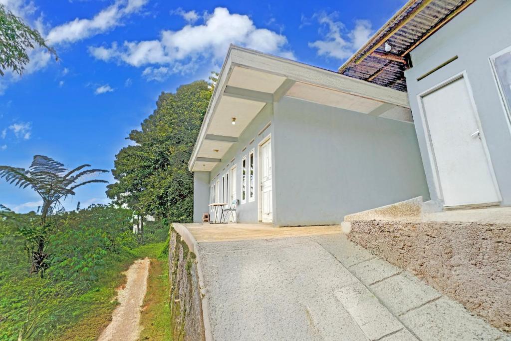 een wit huis met een pad dat er naar toe leidt bij OYO 95065 Villa Ade in Campaka