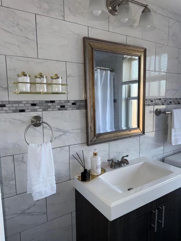 a white bathroom with a sink and a mirror at The Cozy Luxe Retreat, Central West End in Saint Louis