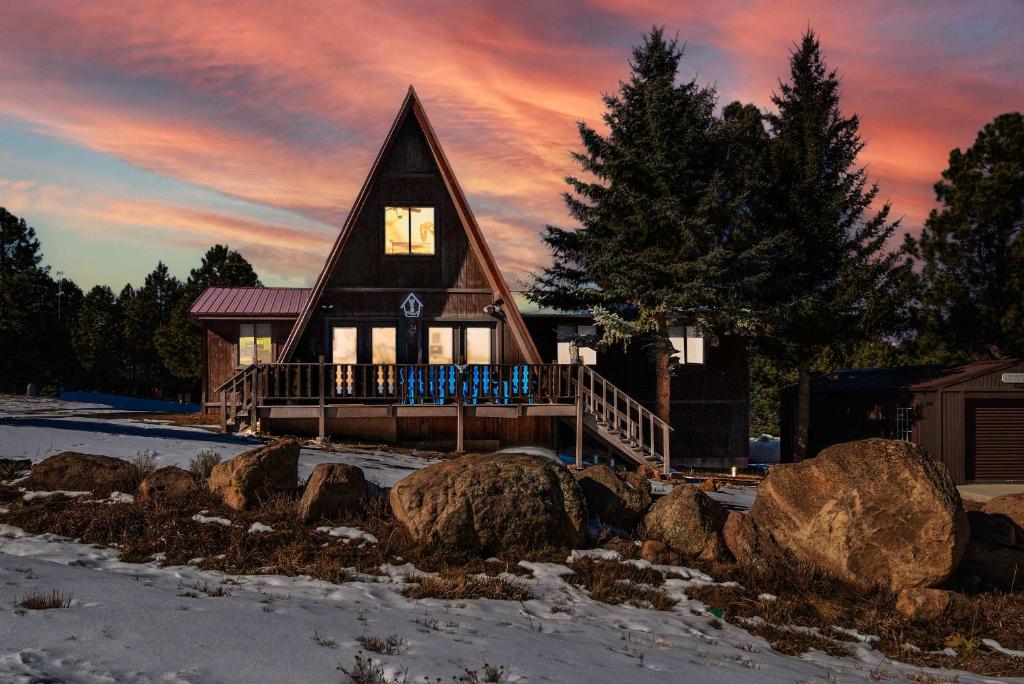 a house in the snow with rocks in front of it at Rustic Mountain Getaway~Golf~Skiing~Hiking in Angel Fire