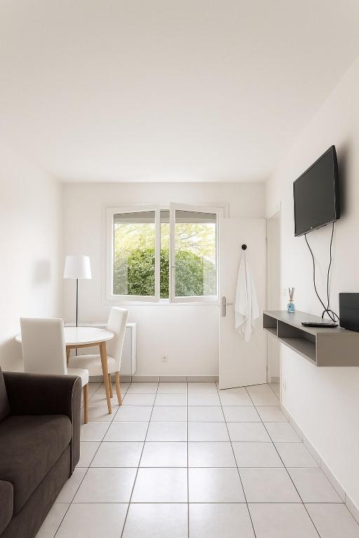 un salon blanc avec un canapé et une table dans l'établissement Studio cosy à 5 min de la mer, à Antibes