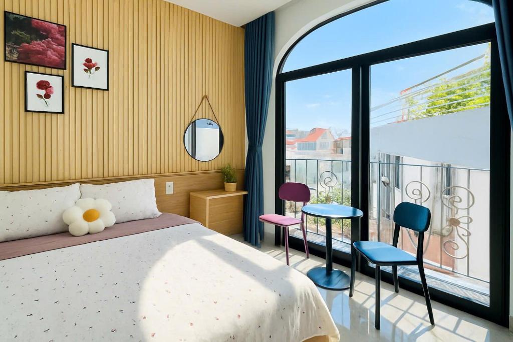 1988 Homestay Vũng Tàu في فنغ تاو: غرفة نوم بسرير وشرفة مع كراسي